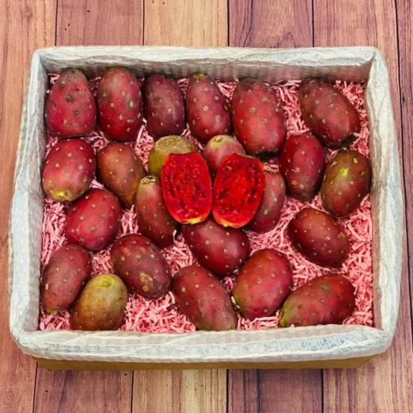 Fresh red cactus pears in a box, showcasing their vibrant red skins and juicy, pink flesh