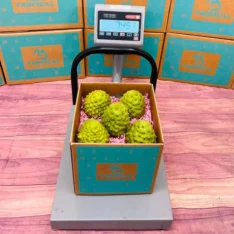 Fresh cherimoya fruits in a box, showcasing their green, scale-like skin and creamy, white flesh