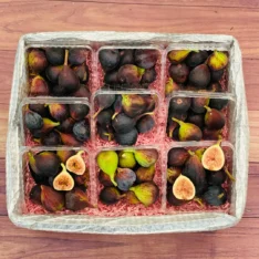 Fresh Black Mission figs in a box, showcasing their deep purple skin and creamy pink interior