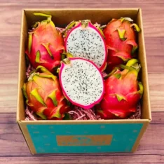 Fresh red dragon fruits in a box, showcasing their vibrant red skin and juicy red pulp with black seeds