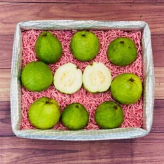 Fresh white guavas in a box, showcasing their vibrant yellow-green skins and crisp white flesh